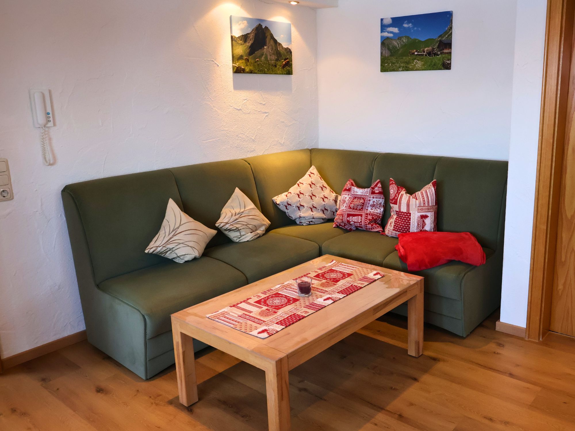 Sitzecke im Wohnbereich der Ferienwohnung Grüntenblick mit Herz-Kissen, Holzdecke und Allgäuer Gemütlichkeit