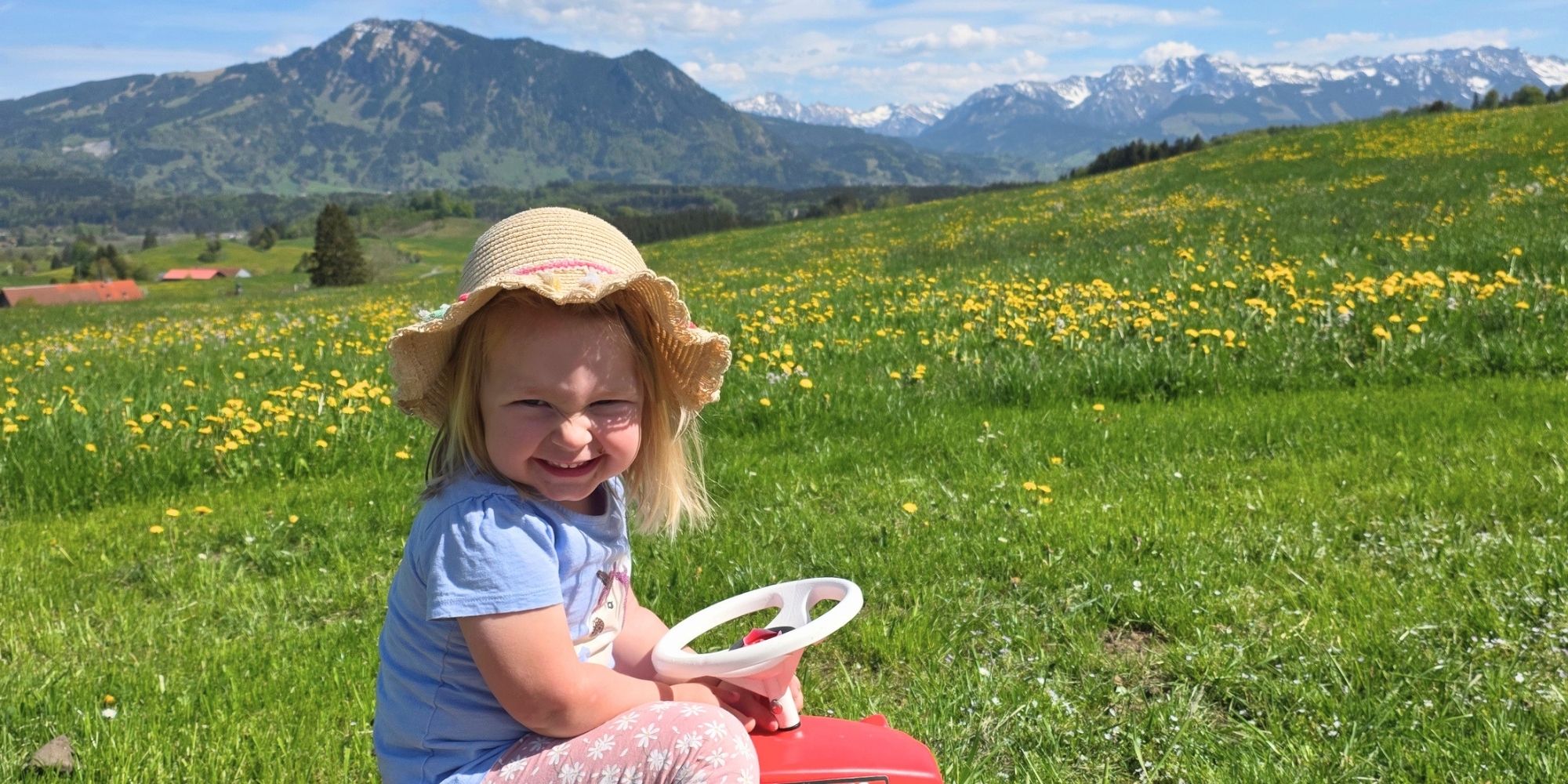 Kind spielt auf Blumenwiese im Allgäu mit Bergblick – Familienurlaub auf dem Bauernhof Ferienhof Eger