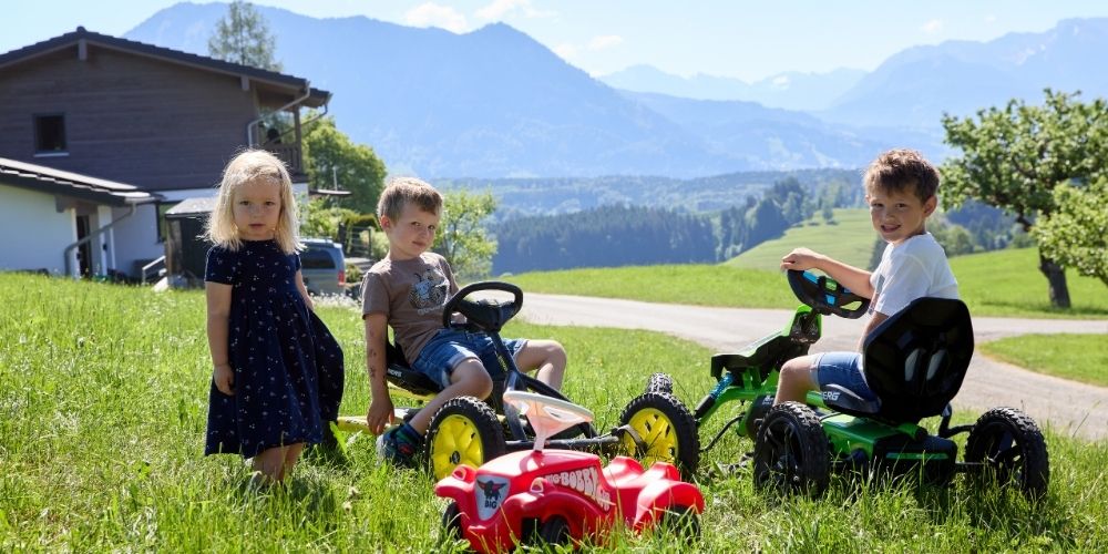 Kinder fahren Go-Kart auf dem Ferienhof Eger mit Bergblick im Allgäu